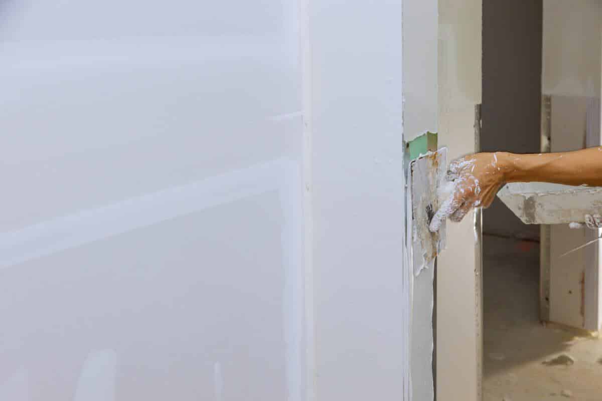 travailleur épandage enduit de plâtre les murs avec du mastic